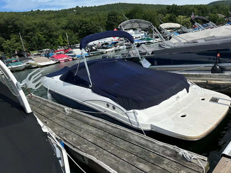 The Image of 2007 Starcraft 2100 IO RE Limited boat docked with cover, surrounded by other boats. - 0