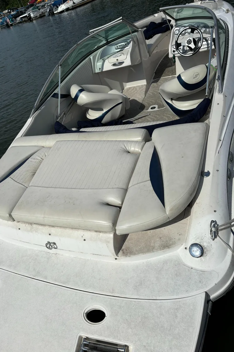 Slide: The Image of 2007 Starcraft 2100 IO RE Limited boat with white seating, steering wheel, and lake backdrop. - 2