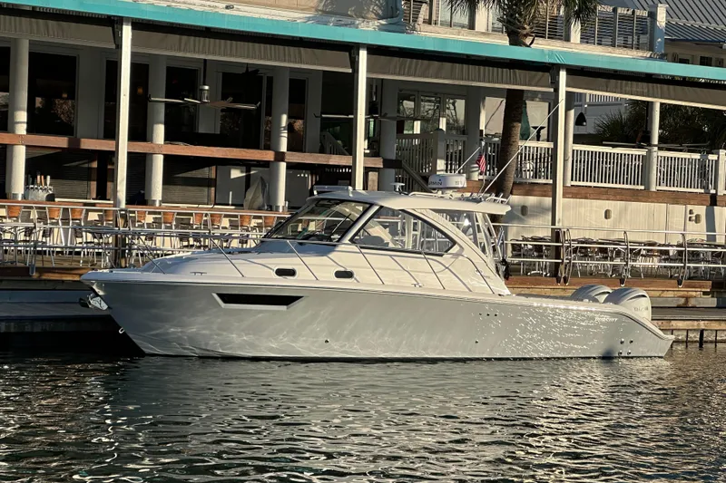 Slide: The Image of 2024 Pursuit OS 325 Offshore boat docked by waterfront restaurant. - 1