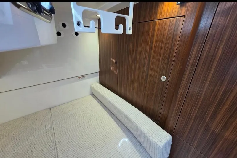 Slide: The Image of 2024 Pursuit OS 325 Offshore cabin interior with wood paneling and cushioned seating. - 10