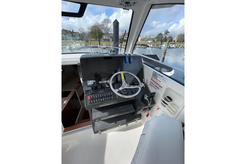 Slide: The Image of 2024 Pursuit OS 325 Offshore boat helm with steering wheel and control panel. - 13