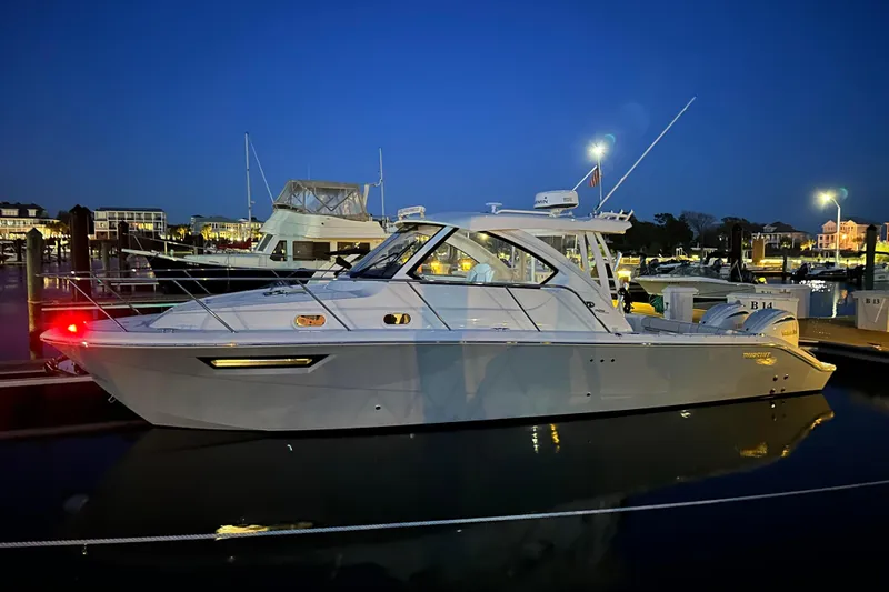 Slide: The Image of 2024 Pursuit OS 325 Offshore boat docked at night, illuminated by marina lights. - 2