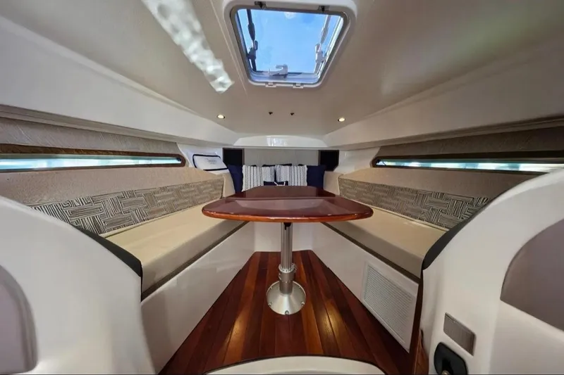 Slide: The Image of 2024 Pursuit OS 325 Offshore cabin interior with wooden table and seating. - 8