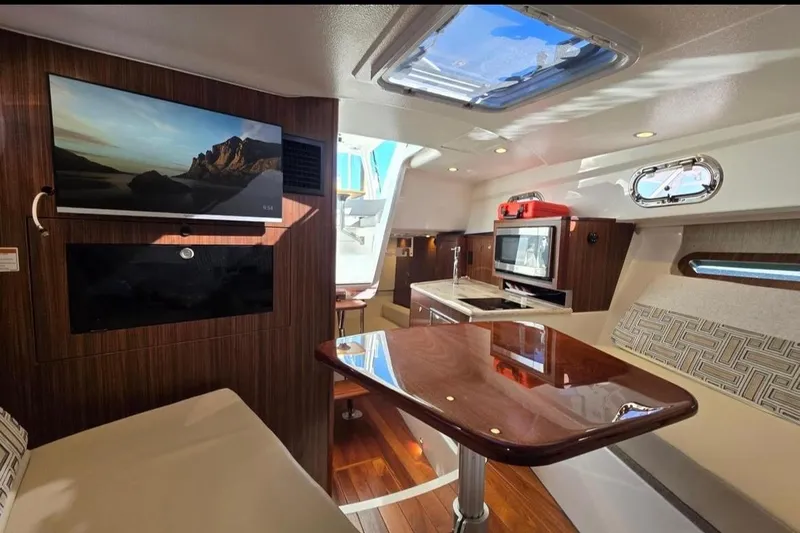 Slide: The Image of 2024 Pursuit OS 325 Offshore interior with modern kitchen, seating, and mounted TV. - 9