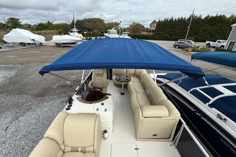 Slide: The Image of 2018 SouthWind V23 L boat with blue canopy and beige seating, parked outdoors. - 10