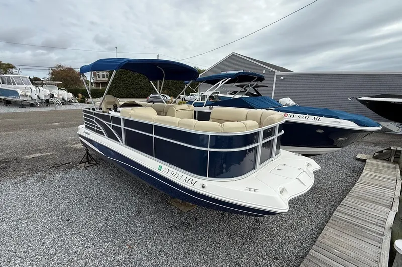 Slide: The Image of 2018 SouthWind V23 L pontoon boat with blue canopy and beige seating, parked on gravel. - 2