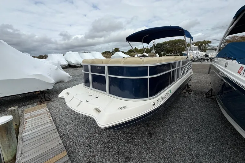 Slide: The Image of 2018 SouthWind V23 L pontoon boat docked on gravel lot under cloudy sky. - 7