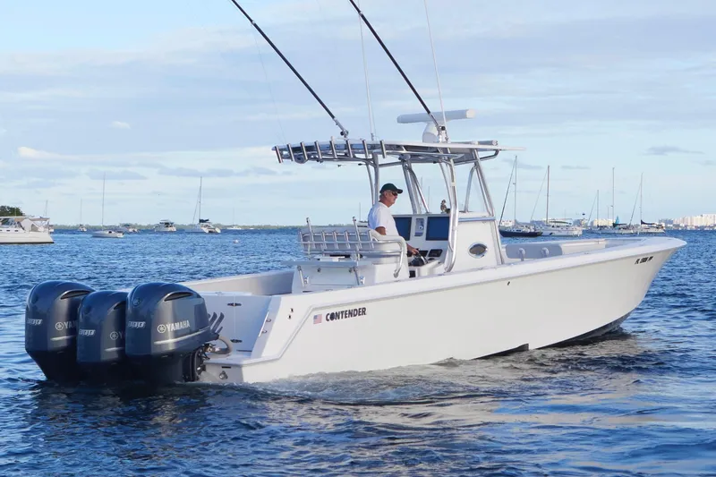 Slide: The Image of 2014 Contender 39 ST boat with triple Yamaha engines cruising on open water. - 2