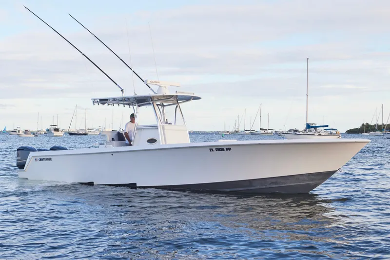 Slide: The Image of 2014 Contender 39 ST boat cruising on water with fishing rods, surrounded by other boats. - 3