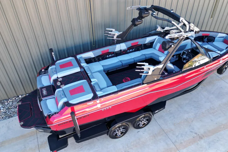 Slide: The Image of 2023 Malibu Wakesetter 25 LSV boat with red and gray seating, parked on a trailer. - 6