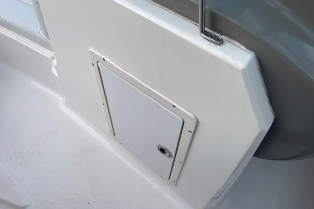 Slide: The Image of 2016 Chaparral 21 H2O Sport boat storage compartment with white panel and handle. - 14