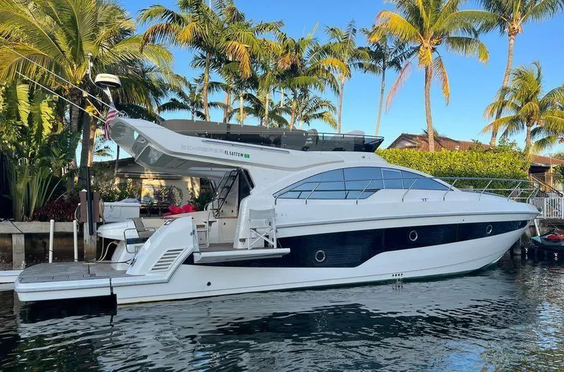 The Image of 2019 Schaefer 510 yacht docked by palm trees, reflecting on calm water. - 0