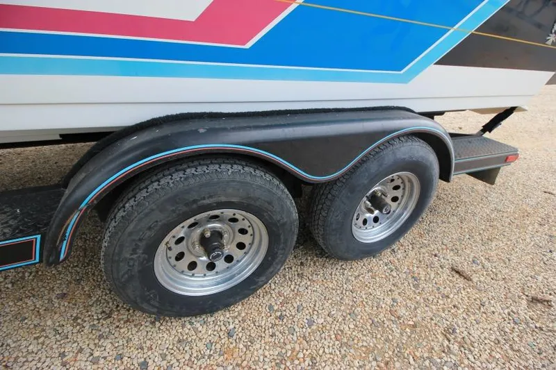 Slide: The Image of 1989 Formula 223 SS boat trailer with dual wheels on gravel surface. - 7