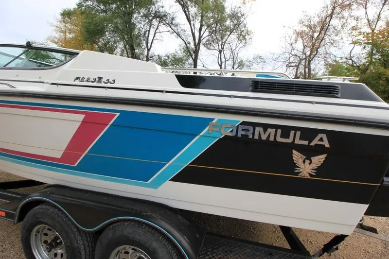 Slide: The Image of 1989 Formula 223 SS boat with colorful graphics on a trailer, surrounded by trees. - 8