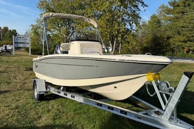 The Image of 2026 Scout 188 Sportfish boat on trailer, parked on grass with trees in background. - 0