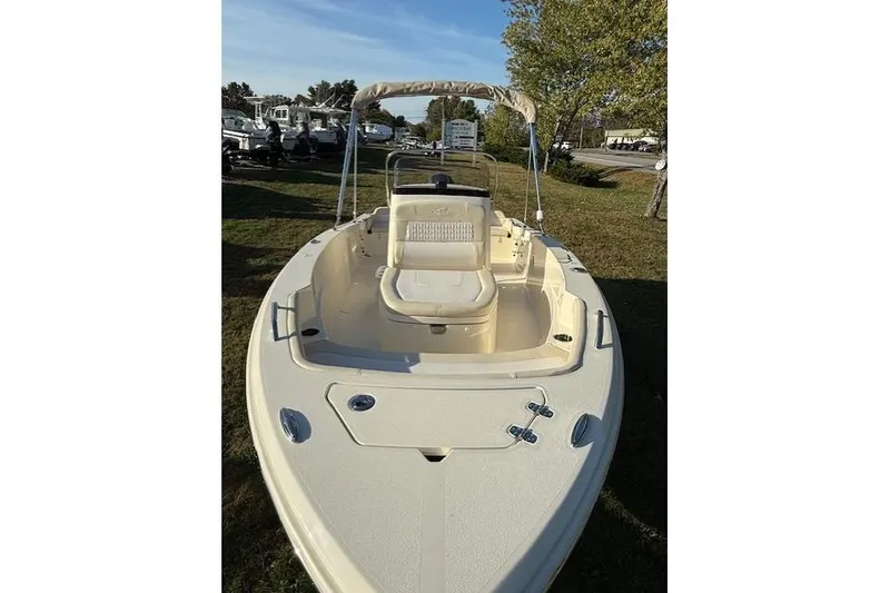Slide: The Image of 2026 Scout 188 Sportfish boat with beige seating and canopy, displayed outdoors. - 4