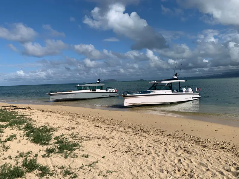 Slide: The Image of Two 2021 Axopar Suntop Brabus Trim boats on a sandy beach under a cloudy sky. - 6