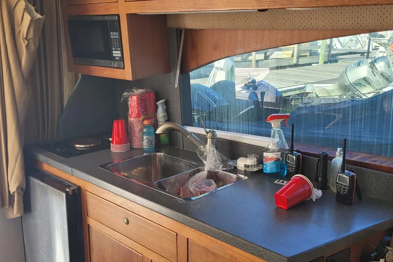 Slide: The Image of 2001 Luhrs 34 Convertible boat kitchen with sink, microwave, and cleaning supplies. - 34