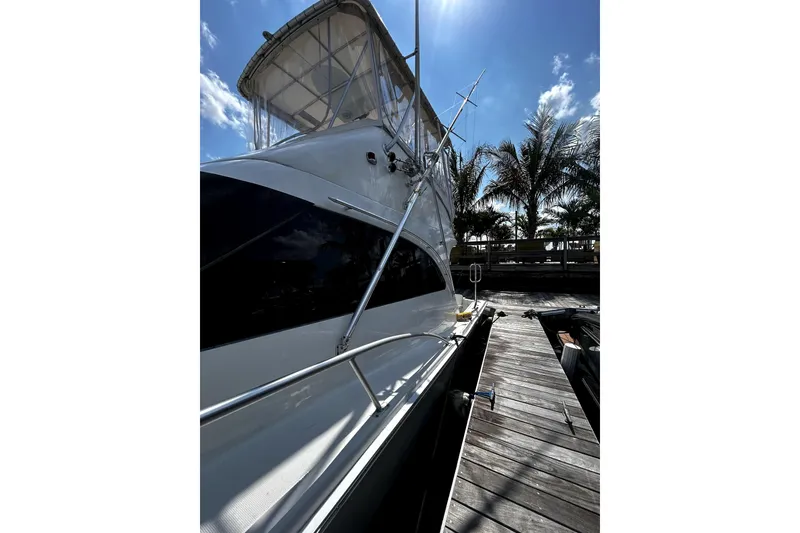 Slide: The Image of 2001 Luhrs 34 Convertible yacht docked under a sunny sky with palm trees. - 5