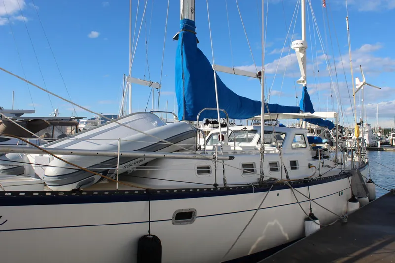 Slide: The Image of 1979 Spencer Yachts 53 sailboat docked, featuring blue sail covers and an inflatable dinghy. - 9