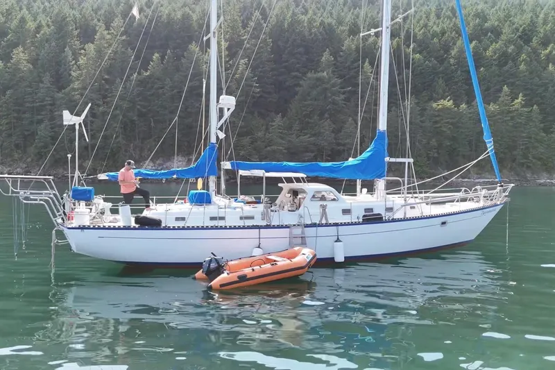The Image of 1979 Spencer Yachts 53 sailboat anchored in serene waters with lush forest backdrop. - 1