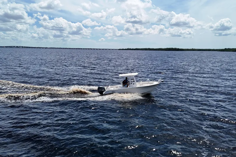 Slide: The Image of 2021 Sea Hunt Ultra 234 boat cruising on open water under a partly cloudy sky. - 10