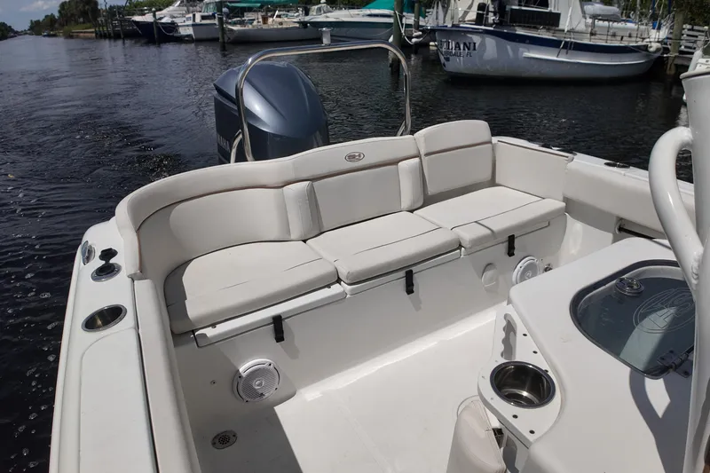 Slide: The Image of 2021 Sea Hunt Ultra 234 boat interior with cushioned seating and motor view. - 15