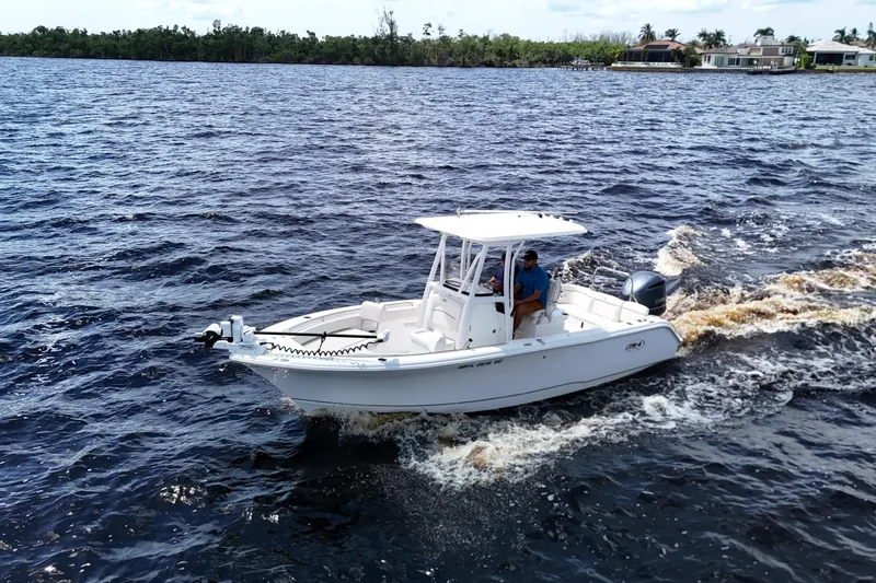 Slide: The Image of 2021 Sea Hunt Ultra 234 boat cruising on a scenic waterway. - 3