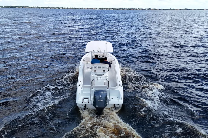 Slide: The Image of 2021 Sea Hunt Ultra 234 boat cruising on open water, rear view. - 5