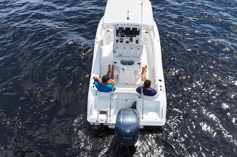 Slide: The Image of 2021 Sea Hunt Ultra 234 boat on water with two people relaxing onboard. - 7