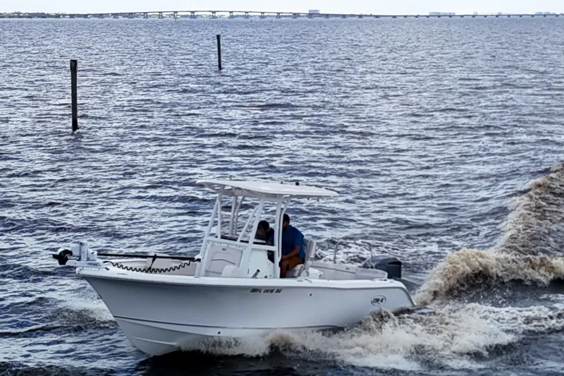 Slide: The Image of 2021 Sea Hunt Ultra 234 boat cruising on a choppy waterway with distant bridge. - 9