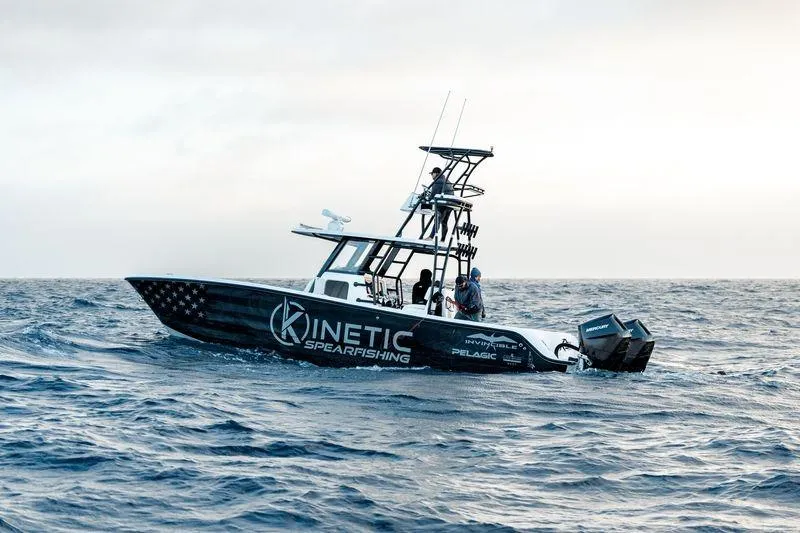 Slide: The Image of 2024 Invincible 33 Catamaran on ocean, featuring "Kinetic Spearfishing" branding. - 2