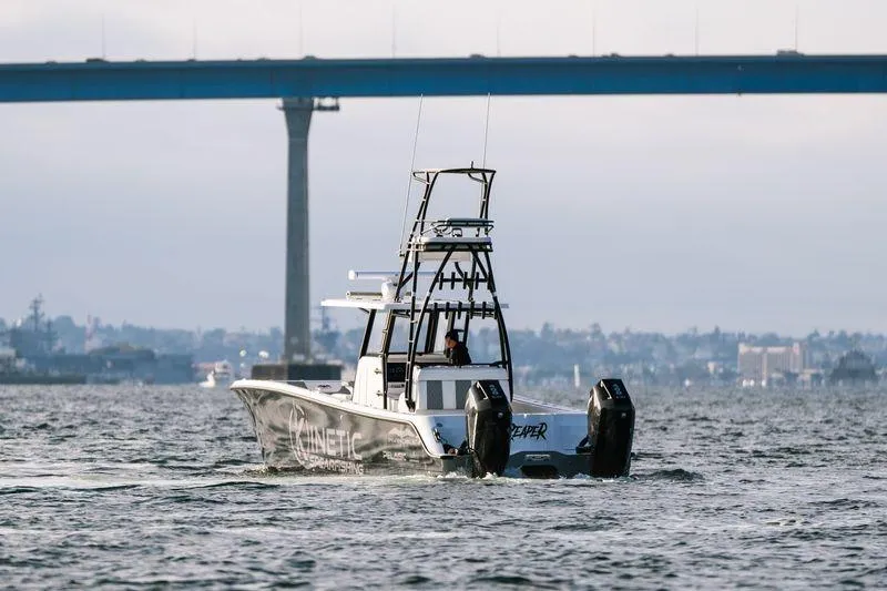 Slide: The Image of 2024 Invincible 33 Catamaran on water near bridge, showcasing sleek design and powerful engines. - 4