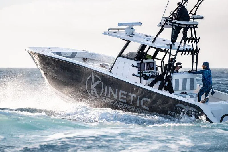 Slide: The Image of 2024 Invincible 33 Catamaran navigating ocean waves, featuring Kinetic Spearfishing branding. - 5