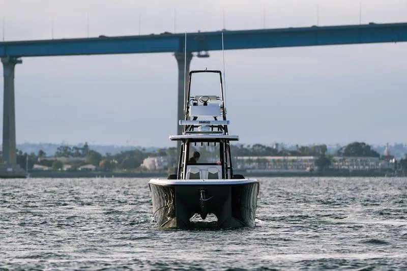 Slide: The Image of 2024 Invincible 33 Catamaran cruising under a bridge on a calm waterway. - 7