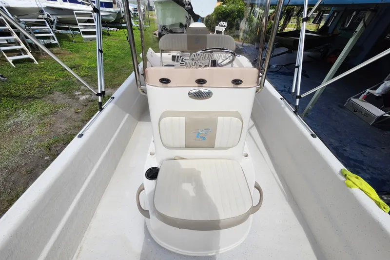 Slide: The Image of 2017 Carolina Skiff 1765 DLX boat interior with seating and console, parked outdoors. - 20