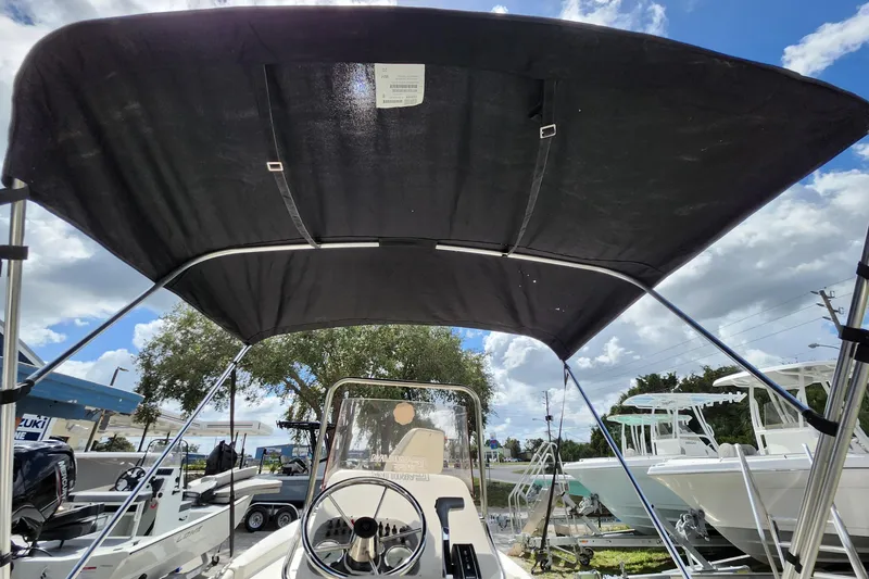 Slide: The Image of 2017 Carolina Skiff 1765 DLX boat with bimini top, steering wheel, and clear sky background. - 22