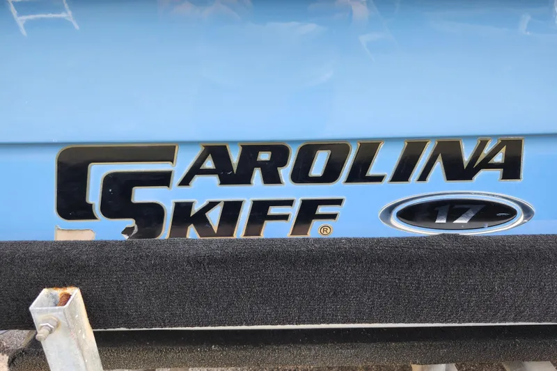 Slide: The Image of 2017 Carolina Skiff 1765 DLX logo on blue boat hull. - 28