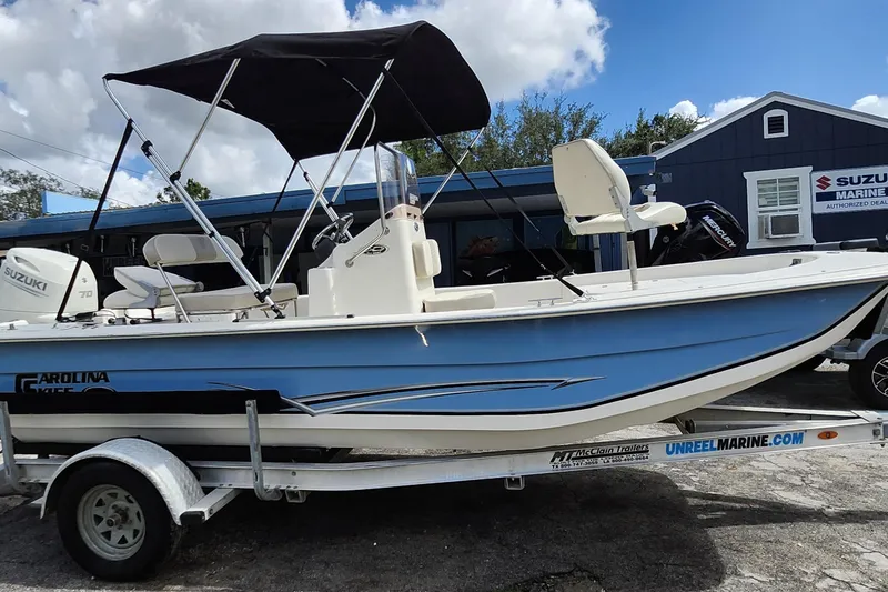Slide: The Image of 2017 Carolina Skiff 1765 DLX boat on trailer, featuring Suzuki engine, parked outdoors. - 31