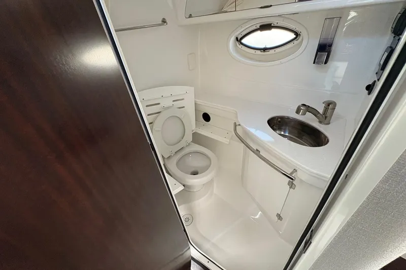 Slide: The Image of 2018 Monterey 335 Sport Yacht bathroom with toilet, sink, and porthole window. - 20