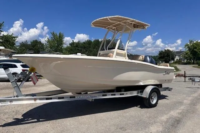 The Image of 2026 Scout 195 Sportfish boat on trailer under clear blue sky. - 0
