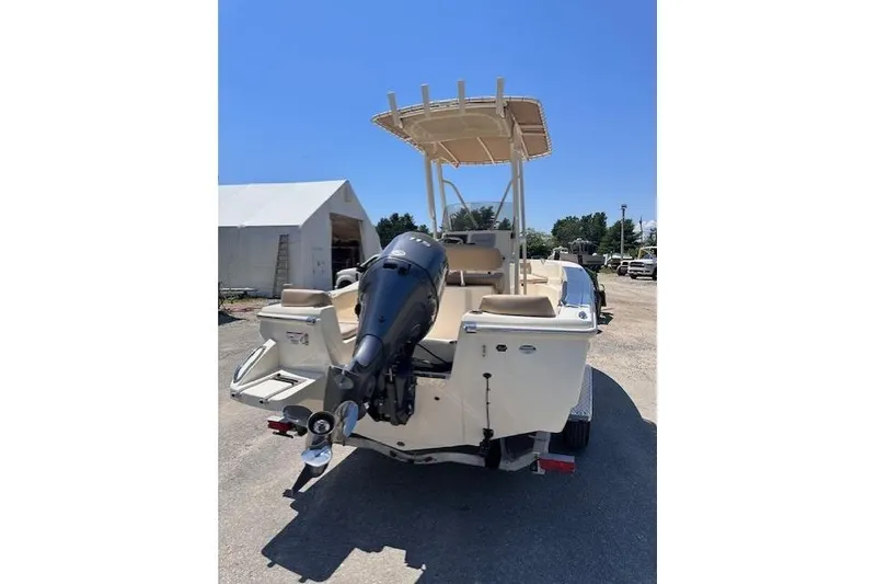 Slide: The Image of 2026 Scout 195 Sportfish boat with outboard motor, parked outdoors on a sunny day. - 2