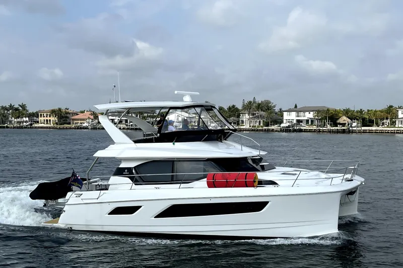 Slide: The Image of Aquila 44 Yacht 2021 cruising on a calm waterway near luxury homes. - 5