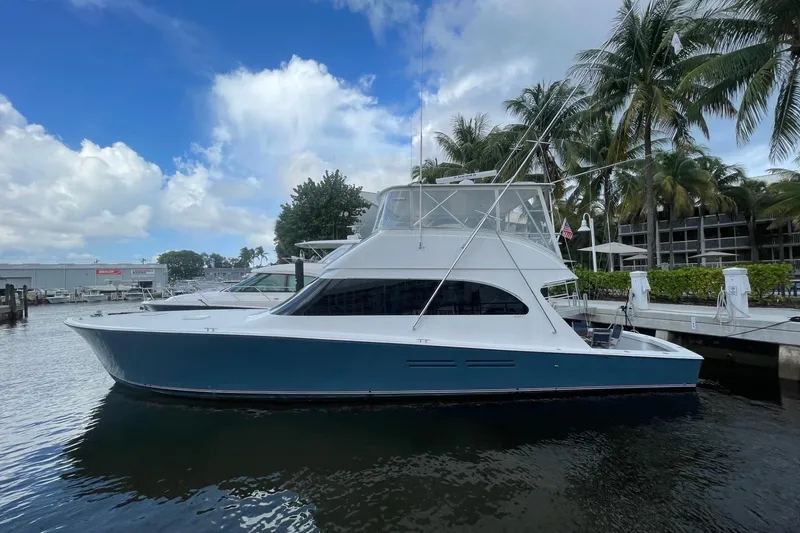 The Image of 2003 Post Flybridge Convertible yacht docked near palm trees under a blue sky. - 0