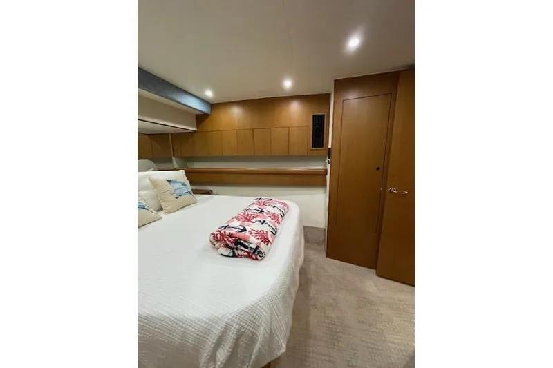 Slide: The Image of 2003 Post Flybridge Convertible cabin with TV, wooden cabinets, and decorative bedding. - 23