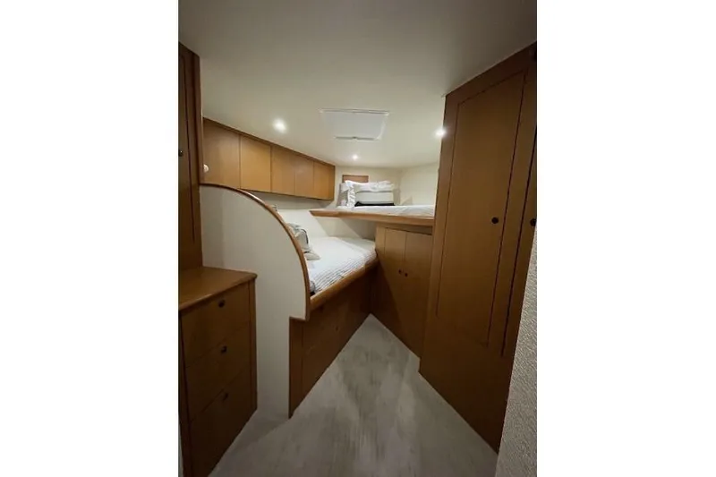 Slide: The Image of 2003 Post Flybridge Convertible cabin with cozy bed and wooden storage cabinets. - 27