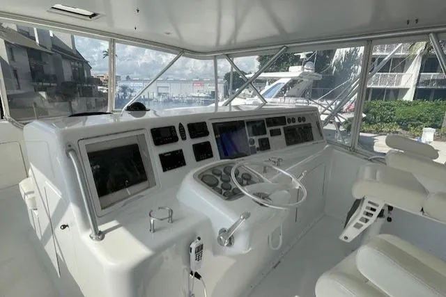 Slide: The Image of 2003 Post Flybridge Convertible yacht interior with helm chairs, overlooking a tropical resort pool. - 47