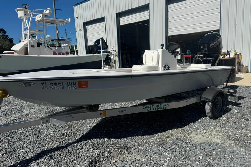 Slide: The Image of 2023 Lagoon 14 boat on trailer, parked outside a warehouse. - 0