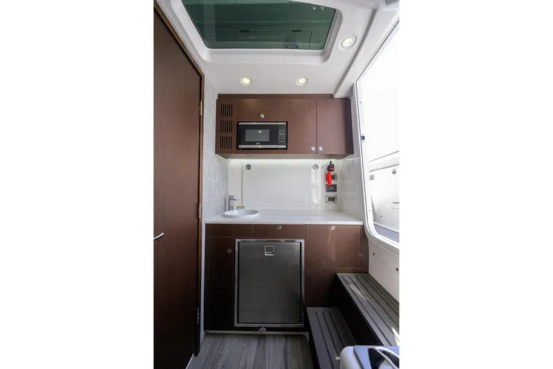 Slide: The Image of 2024 Everglades 455 Center Console interior with kitchenette, featuring microwave, sink, and fridge. - 39