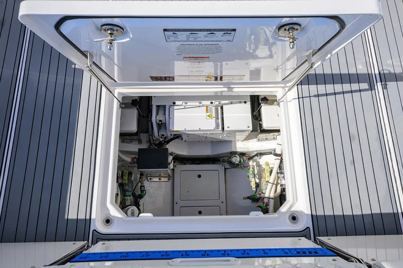 Slide: The Image of 2024 Everglades 455 Center Console boat storage compartment with open hatch, showcasing internal components. - 44